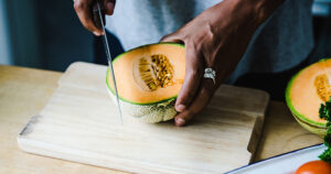 hand cutting cantaloupe with a knife
